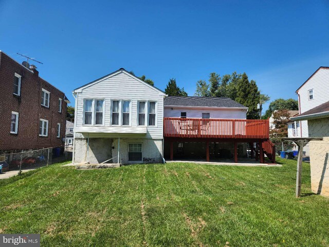 rear view of property featuring a wooden deck, a yard, and a patio