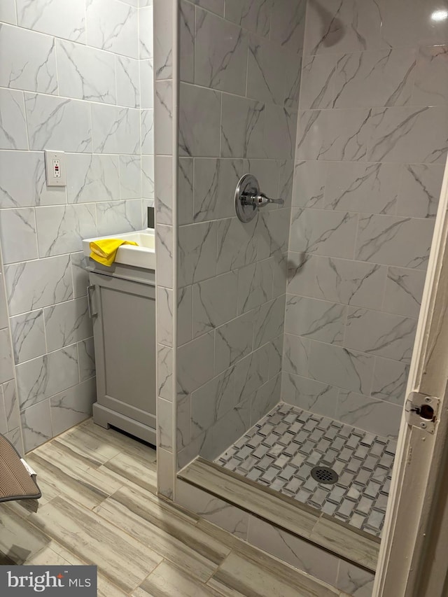 bathroom featuring tile walls, a tile shower, and vanity