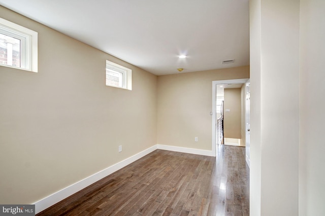 basement with wood finished floors, visible vents, and baseboards