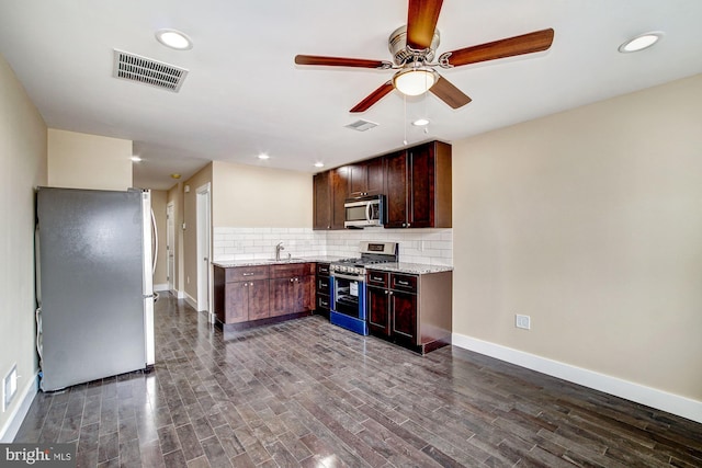 kitchen with stainless steel appliances, visible vents, backsplash, a sink, and wood finished floors