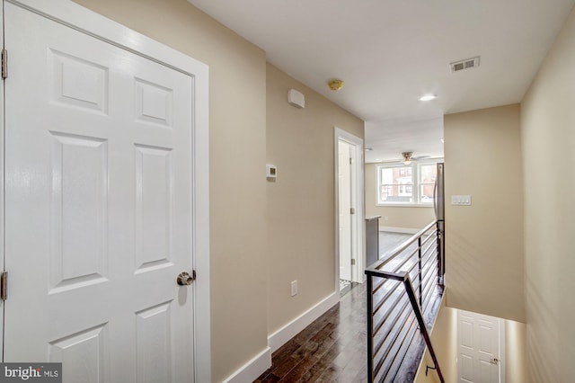 hall featuring dark wood finished floors, an upstairs landing, visible vents, and baseboards