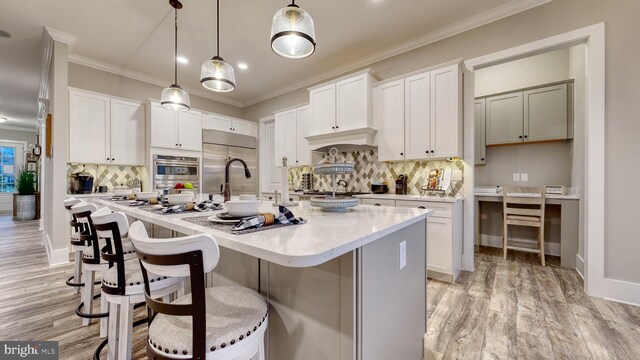 kitchen featuring an island with sink, light wood-type flooring, and tasteful backsplash