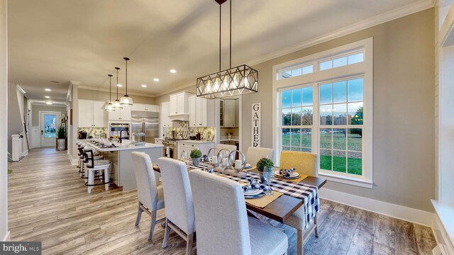 dining area with light hardwood / wood-style floors and ornamental molding