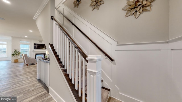 stairs featuring hardwood / wood-style flooring and crown molding