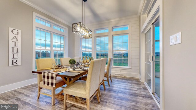 dining room with a notable chandelier, hardwood / wood-style flooring, and crown molding