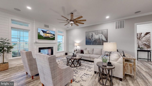 living room with crown molding, a wealth of natural light, ceiling fan, and light hardwood / wood-style floors