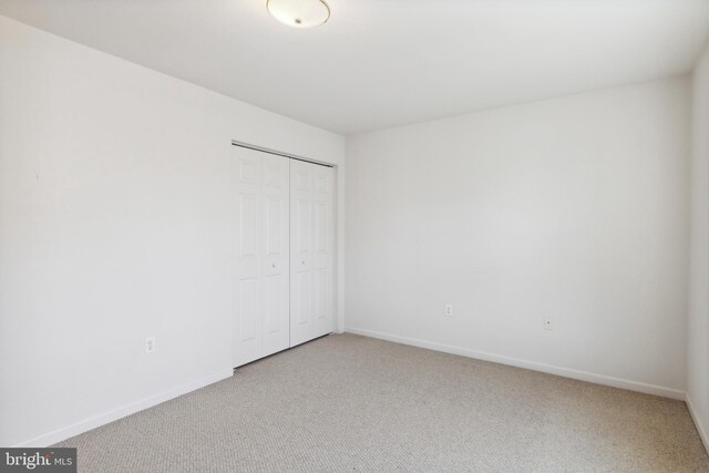 unfurnished bedroom with a closet and light colored carpet