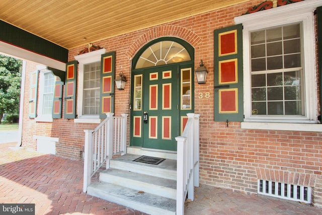 property entrance with a porch and brick siding