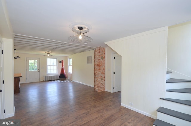 interior space featuring baseboards, visible vents, radiator heating unit, stairway, and wood finished floors