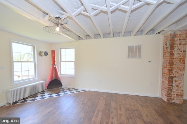 spare room with radiator heating unit, wood finished floors, visible vents, and baseboards