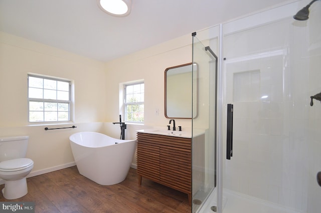 full bath featuring a freestanding bath, toilet, vanity, a shower stall, and wood finished floors