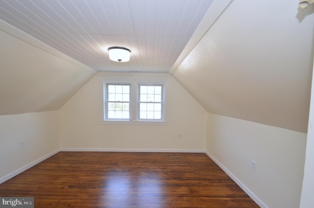 bonus room with dark wood-style floors, baseboards, and vaulted ceiling