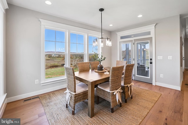 dining area with light wood finished floors, plenty of natural light, visible vents, and baseboards