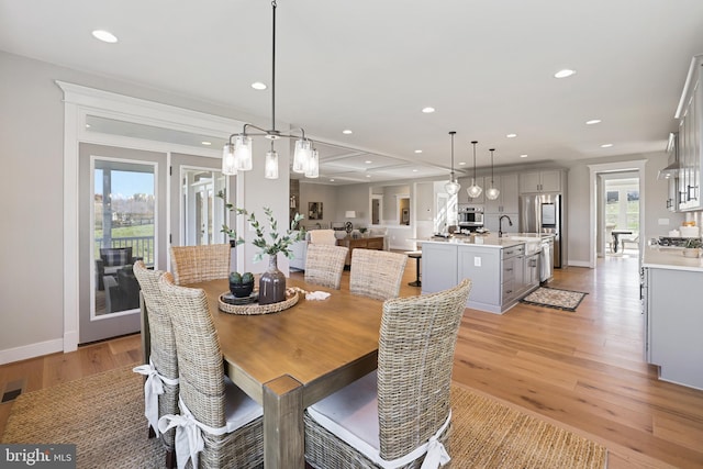 dining room with light wood finished floors, baseboards, and recessed lighting