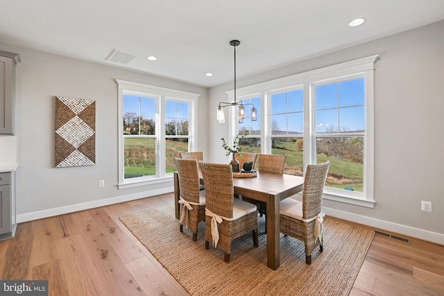 dining room with light wood-style flooring, visible vents, and baseboards