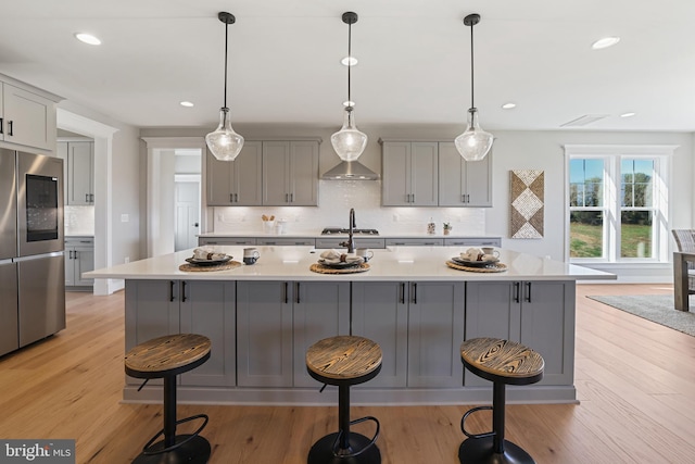 kitchen featuring a center island with sink, light countertops, gray cabinetry, light wood-type flooring, and smart refrigerator