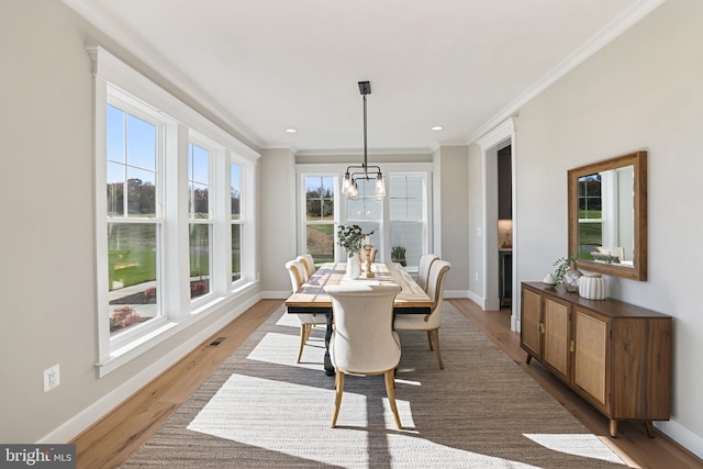 dining area featuring baseboards, wood finished floors, visible vents, and crown molding