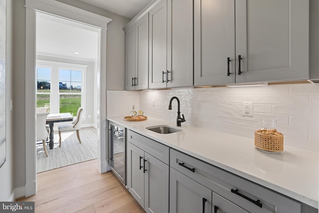 kitchen featuring tasteful backsplash, gray cabinets, a sink, and light countertops