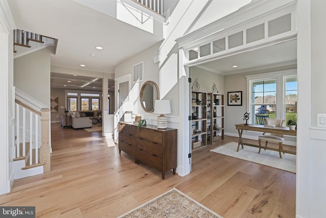 foyer entrance with stairs, a wealth of natural light, light wood-style flooring, and crown molding