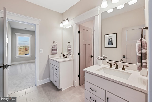 full bath featuring tile patterned flooring, baseboards, two vanities, and a sink