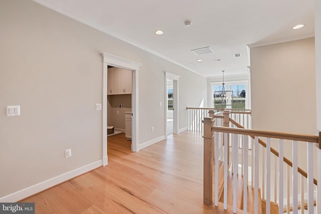 hall with light wood finished floors, baseboards, crown molding, an upstairs landing, and recessed lighting