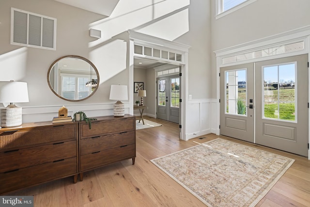 entrance foyer with light wood-style flooring, visible vents, and french doors