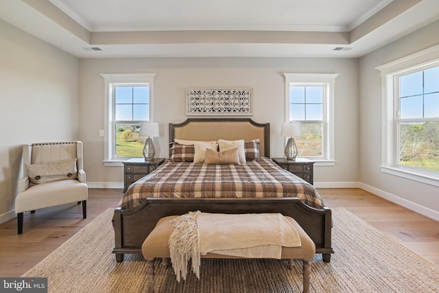 bedroom with a tray ceiling, multiple windows, and visible vents