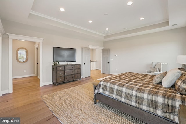 bedroom featuring light wood-style floors, baseboards, and a tray ceiling