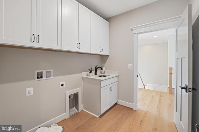 laundry area with hookup for a washing machine, cabinet space, hookup for an electric dryer, a sink, and light wood-type flooring