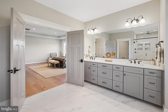 bathroom featuring marble finish floor, double vanity, walk in shower, and a sink