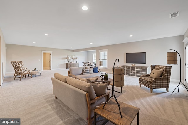 living area with recessed lighting, visible vents, baseboards, and light colored carpet