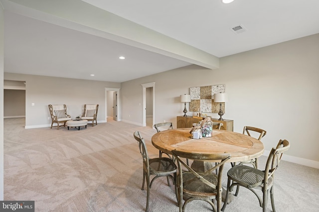 dining space featuring baseboards, visible vents, beam ceiling, and light colored carpet