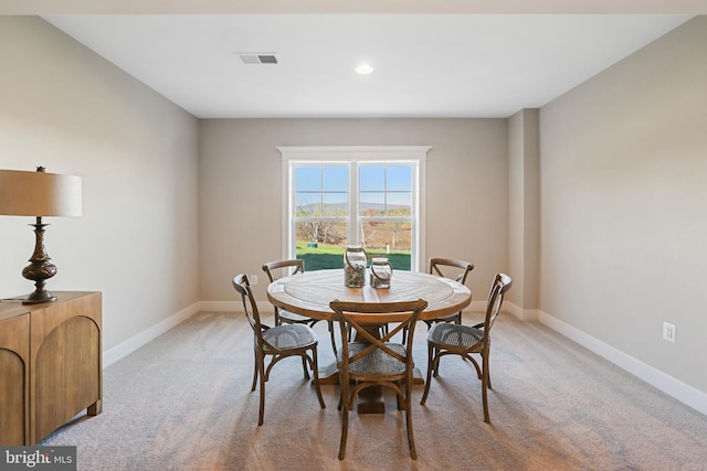 dining space featuring baseboards, visible vents, and light colored carpet