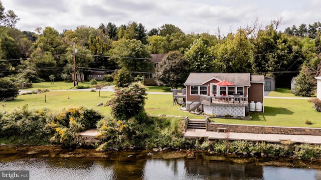 rear view of house with a yard and a deck with water view