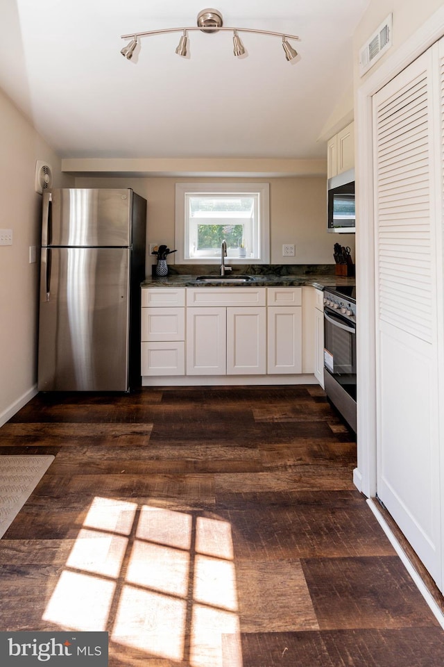 kitchen featuring dark wood-type flooring, appliances with stainless steel finishes, white cabinetry, and sink