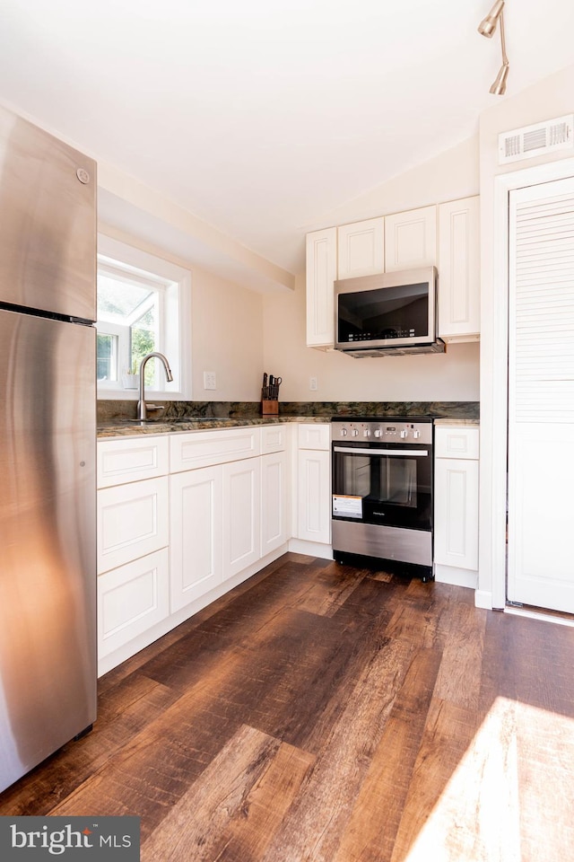 kitchen with lofted ceiling, stainless steel appliances, dark hardwood / wood-style floors, and white cabinets