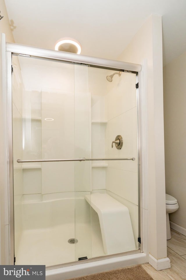 bathroom with a shower with shower door, toilet, and hardwood / wood-style flooring