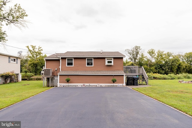 view of front of house with a wooden deck, central AC unit, and a front yard