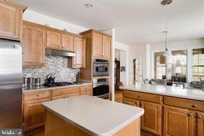 kitchen with tasteful backsplash, stainless steel appliances, a center island, and pendant lighting