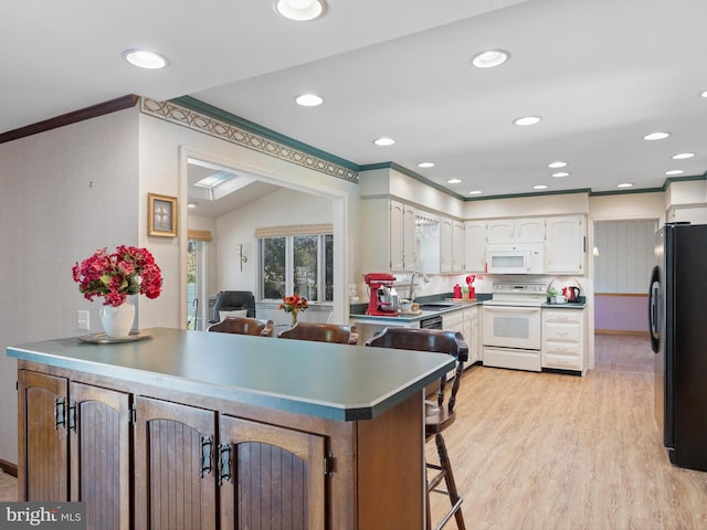 kitchen with light wood-type flooring, white appliances, kitchen peninsula, sink, and vaulted ceiling