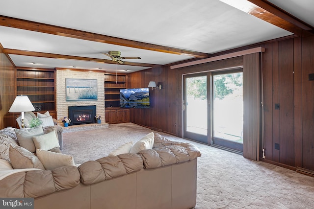 living room featuring light carpet, wooden walls, a brick fireplace, ceiling fan, and beam ceiling