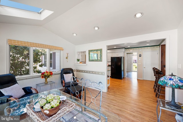 interior space featuring vaulted ceiling with skylight and light wood-type flooring