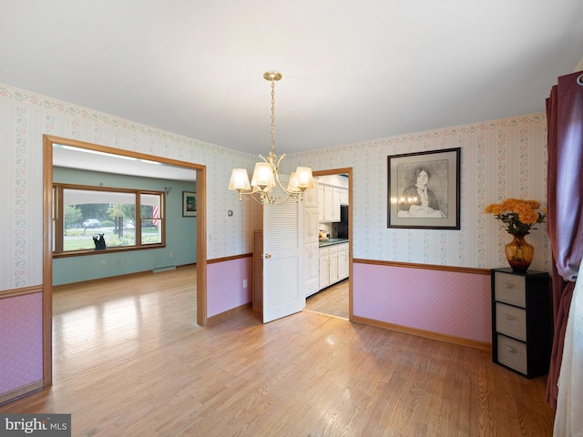 unfurnished dining area featuring light hardwood / wood-style flooring and a chandelier