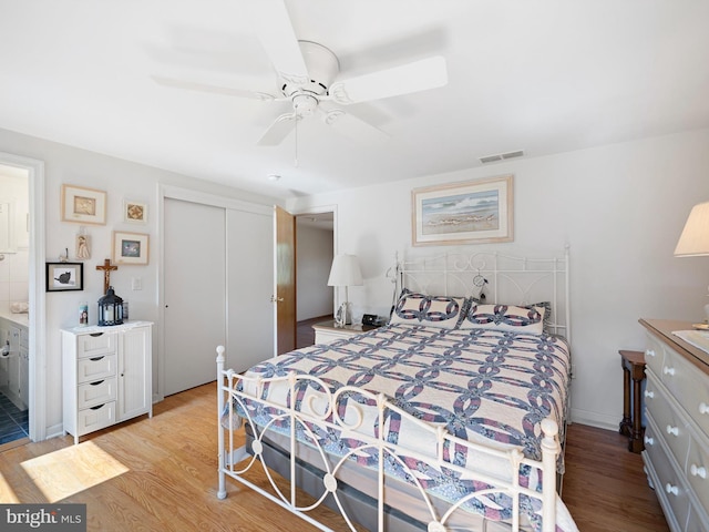 bedroom featuring light hardwood / wood-style flooring, ensuite bath, a closet, and ceiling fan