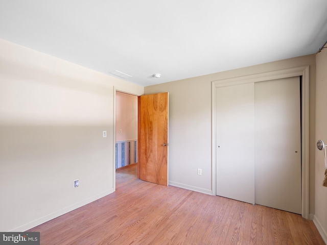 unfurnished bedroom featuring light hardwood / wood-style flooring and a closet