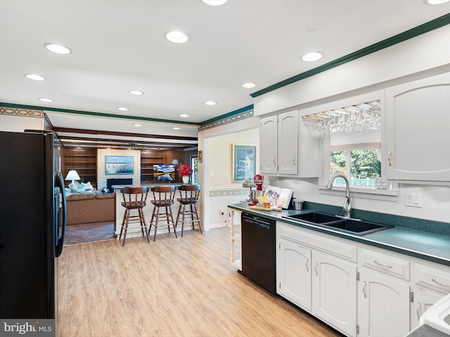 kitchen featuring light wood-type flooring, black appliances, white cabinets, and sink