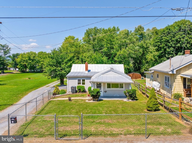 view of front of home featuring metal roof, central AC, a fenced front yard, and a front yard