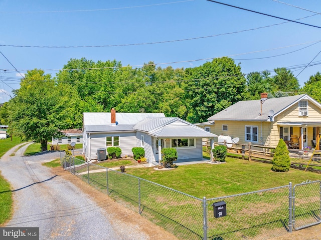 view of front facade featuring driveway, a fenced front yard, a front lawn, a porch, and central AC