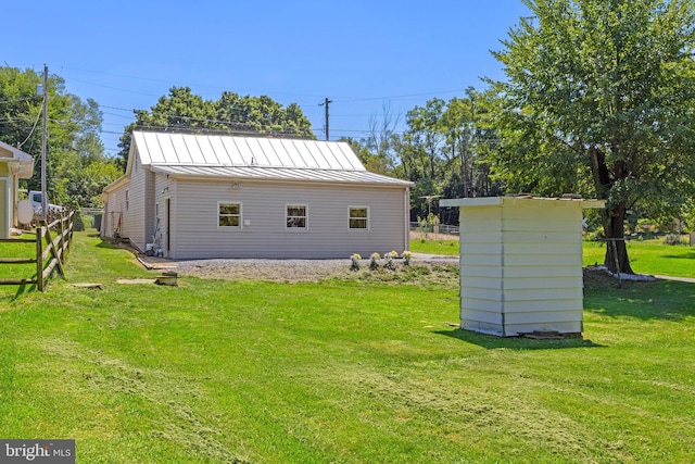 exterior space with a yard, a standing seam roof, an outdoor structure, and fence