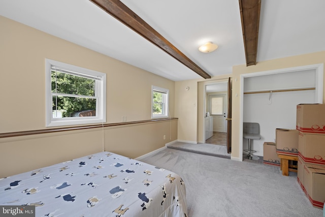 carpeted bedroom featuring a closet and beamed ceiling